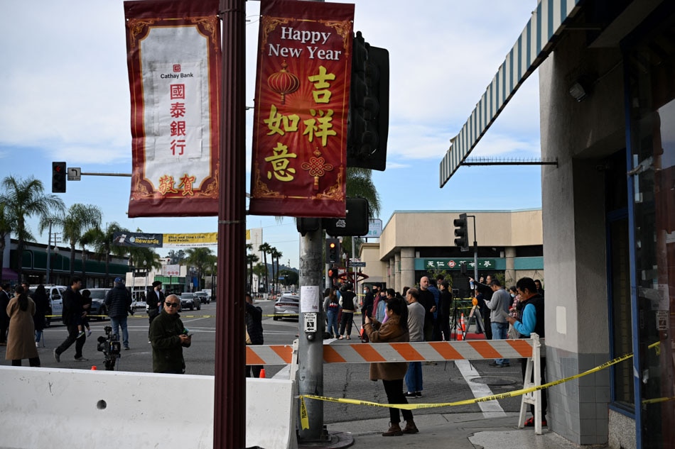 Local residents watch police investigate the scene of a mass shooting in Monterey Park, California, on January 22, 2023. - Ten people have died and at least 10 others have been wounded in a mass shooting in a largely Asian city in southern California, police said, with the suspect still at large hours later. Robyn Beck,  AFP