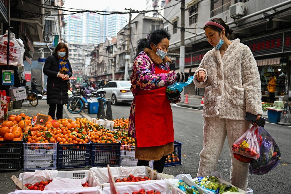 A customer (right) buys fruit at a local market in Wuhan, in China's central Hubei province, on Jan. 23, 2023. Exactly 3 years ago, China enforced its first lockdown related to the COVID-19 virus on Wuhan, the epicenter of what would become a global pandemic. Hector Retamal, AFP/File 