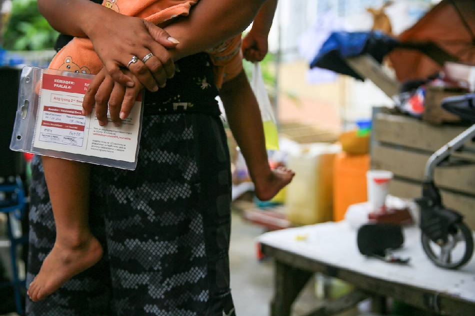 A mother carries her child after being inoculated with a COVID-19 booster shot in Scout Santiago in Quezon City on September 29, 2022. Along with the administration of COVID-19 vaccines, the DOH hopes to address other health concerns and issues of the homeless families such as malnutrition and routine immunization. Jonathan Cellona, ABS-CBN News