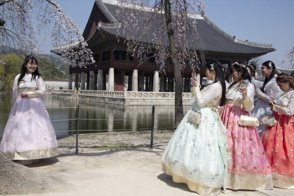 Tourists wearing Hanbok, a Korean traditional dress, take pictures during a visit to the Gyeongbokgung Palace in Seoul, South Korea on March 30, 2023. Jeon Heon-Kyun, EPA-EFE/File