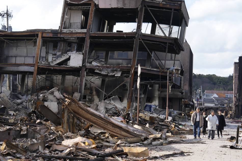 People walk past burnt remains of building structures following an earthquake in Wajima, Ishikawa Prefecture, Japan, Jan. 4, 2024. Franck Robichon, EPA-EFE 