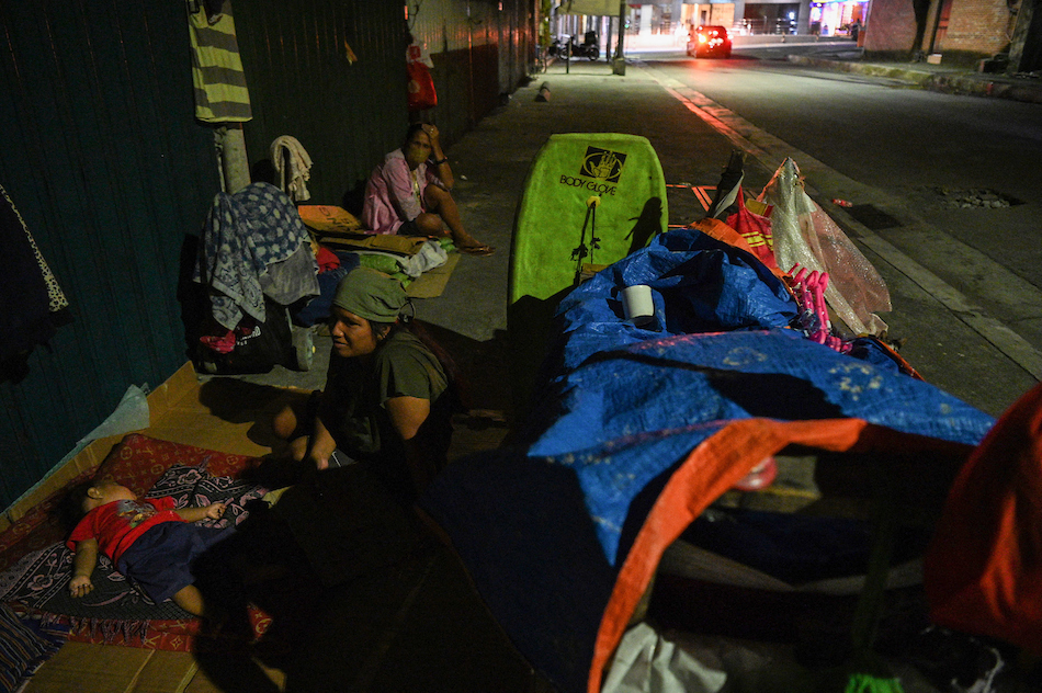 This photo taken on November 29, 2022 shows a group of homeless people resting next to their pushcart outside an abandoned building in Quezon City, suburban Manila. Ted Aljibe, AFP/File 