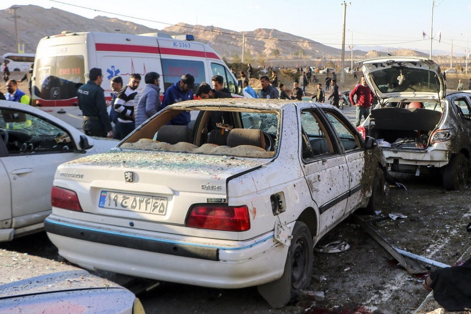 Damaged cars are seen as people try to help victims after an explosion next to the tomb of Iran