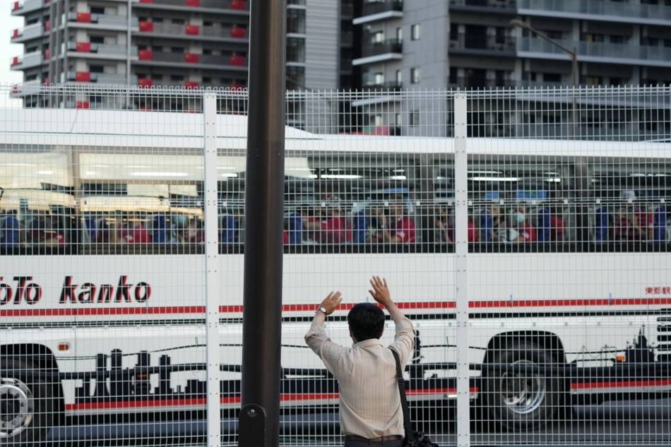 A Japanese man waves to a bus carrying athletes as it leaves the Olympic Village in Tokyo, Japan, 19 July 2021. EPA-EFE/FRANCK ROBICHON