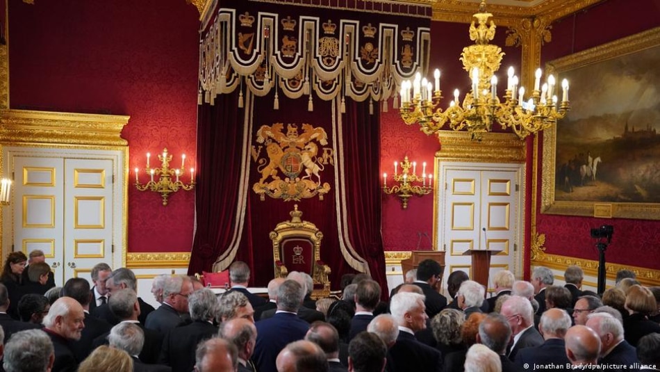Members of the Accession Council assembled before the throne still bearing the 'ER' cypher of Elizabeth II
